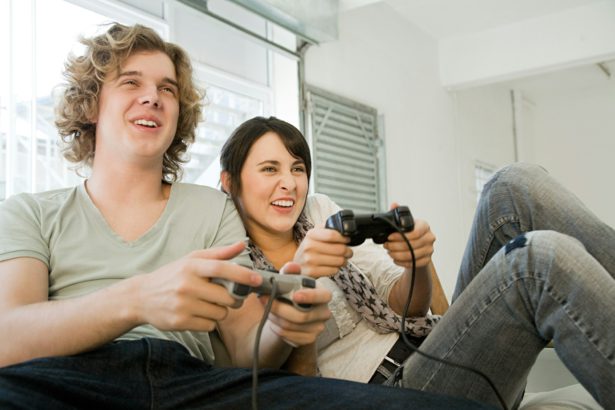 Teenage couple playing with games consoles